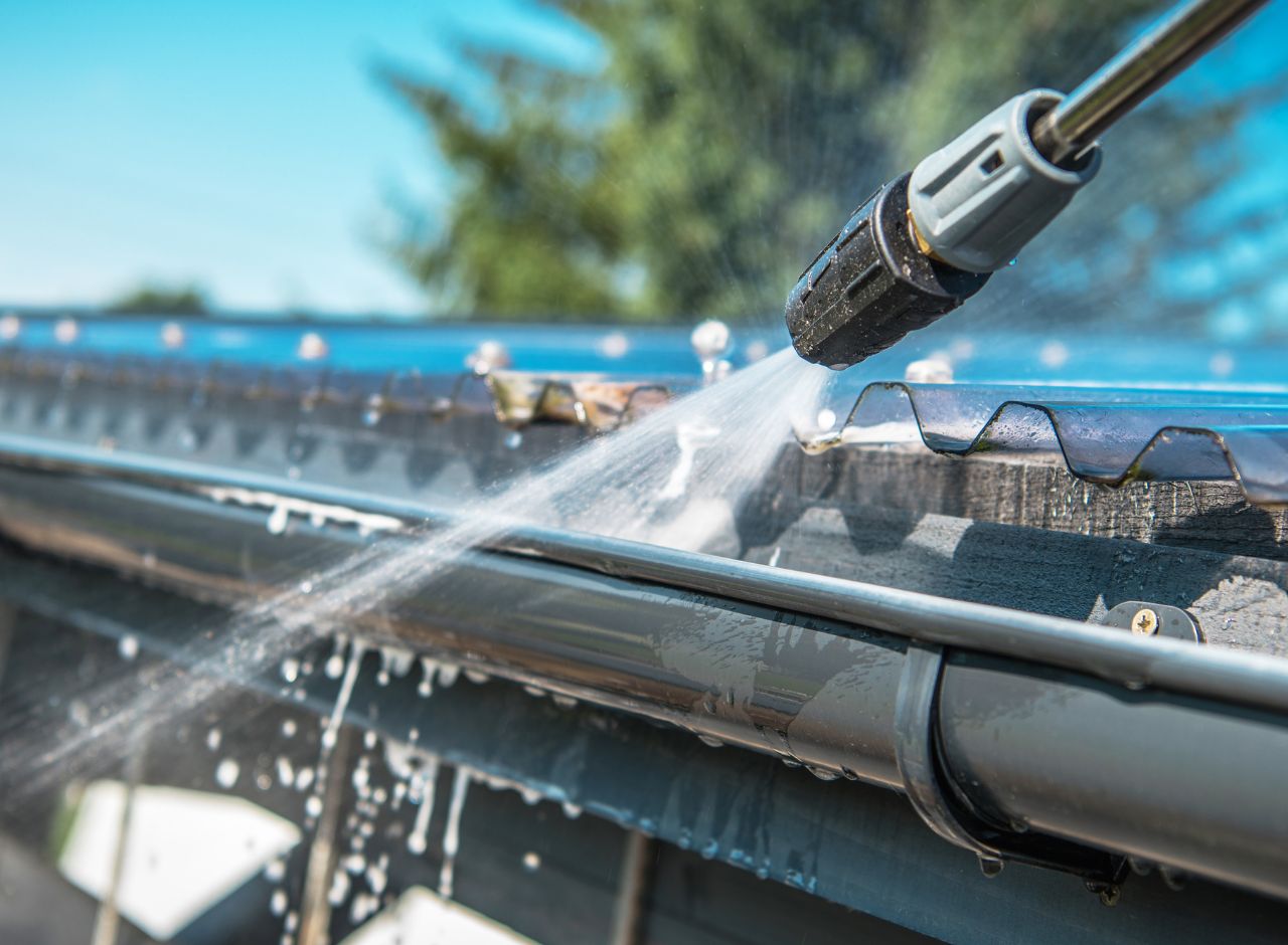 Pressure washing the gutters on house roof
